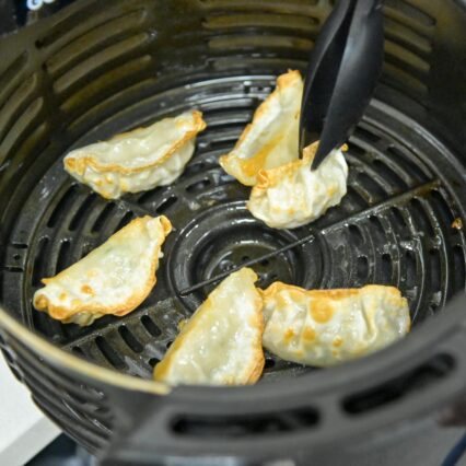 Gyoza being flipped in air fryer basket